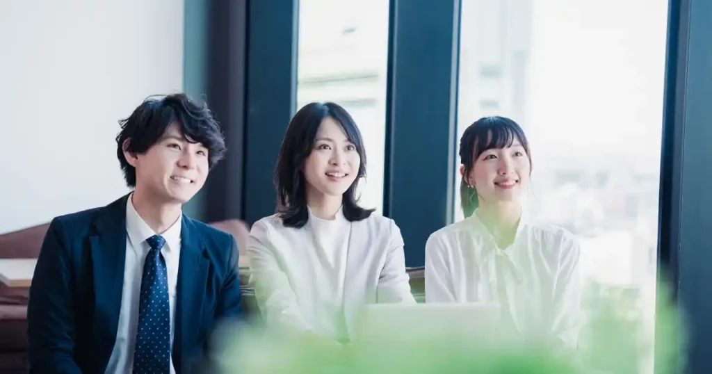 就活座談会に参加する学生たちが、リラックスした表情で話を聞いている場面。明るい会場で、基本マナーが実践されている様子をイメージ。