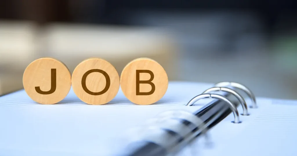 『JOB』と書かれた木製ブロックがリングノートの上に置かれている。ジョブ型採用の求人情報取得方法を象徴するイメージ。