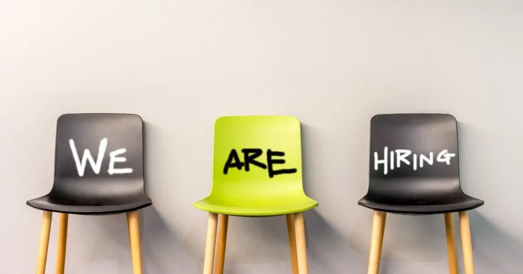3つの椅子が並び、中央の椅子に『WE ARE HIRING』と書かれたデザイン。ジョブ型採用に対応するための採用戦略を象徴するイメージ。