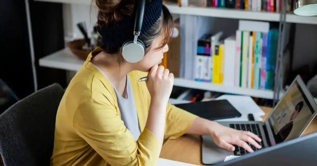 ヘッドホンを装着し、オンライン学習に取り組む女性。IT業界を目指すための資格取得に向けた勉強の様子。