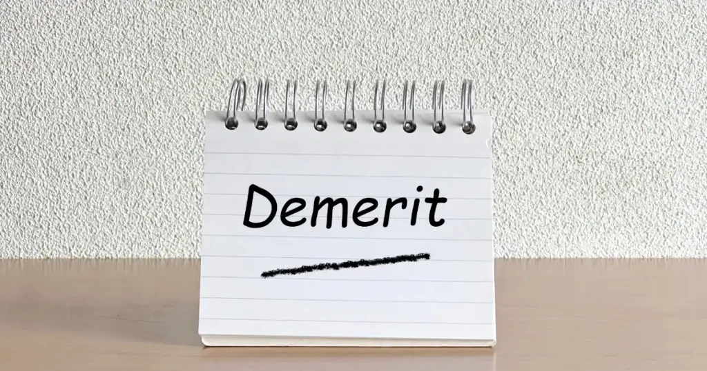 「Demerit」と書かれたメモ帳が机の上に置かれている画像。ボーナスをもらってから退職する際のデメリットについて説明するセクションに使用され、注意点やリスクを強調するビジュアルとして機能しています。