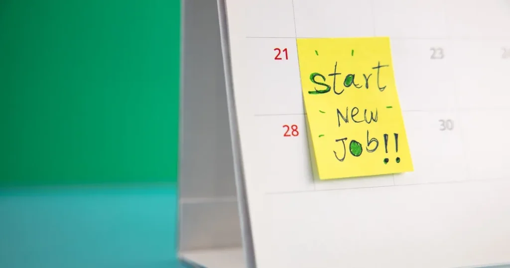 カレンダーに貼られた「Start New Job!!」と書かれた黄色い付箋。新しい仕事の始まりを示唆するポジティブなイメージ。