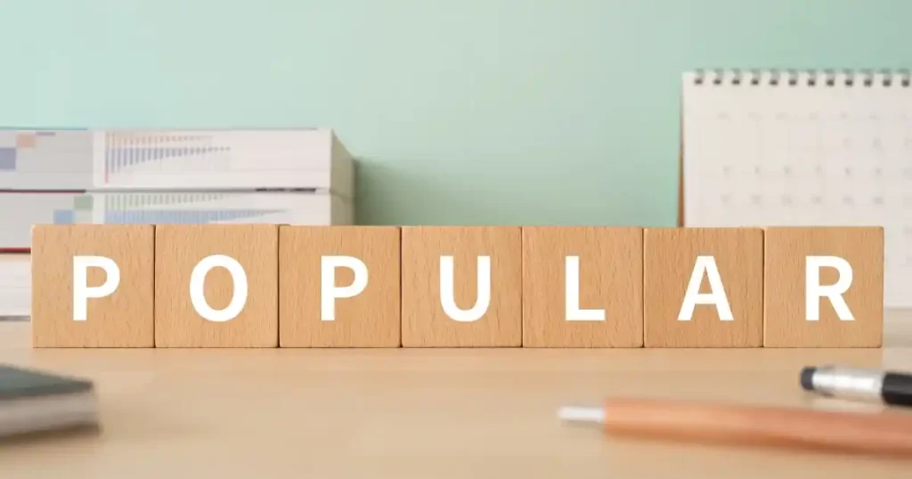木製ブロックで「POPULAR」と書かれたデスク:転職市場で人気の業界や注目される分野を象徴するイメージ。