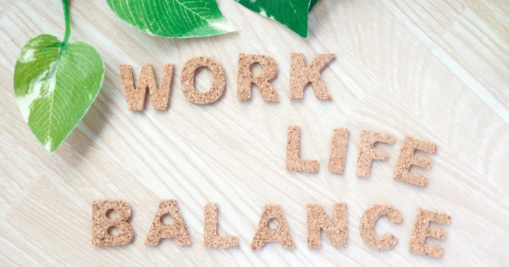 「WORK LIFE BALANCE」と書かれたコルク文字と葉の装飾：自然の調和をイメージし、仕事と私生活のバランスの重要性を表現。