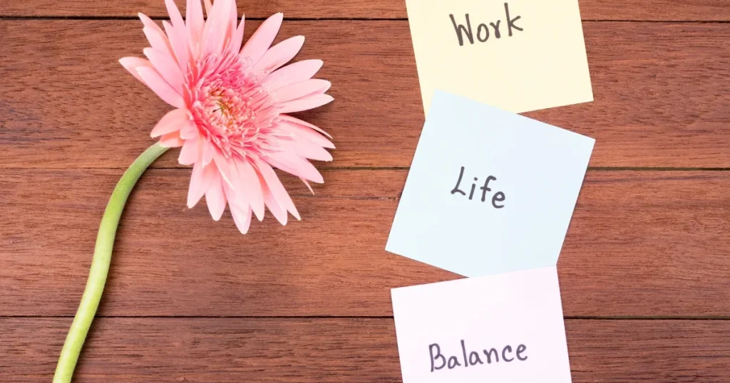「Work」「Life」「Balance」と書かれたメモと花：仕事と私生活の調和がもたらす幸福感と充実感を象徴するイメージ。