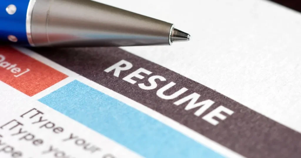履歴書（RESUME）の上に置かれたペン：志望動機を考える際に意識すべきポイントを示すイメージ。