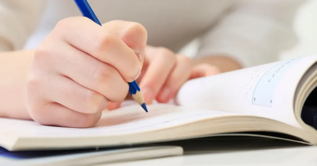 ノートに鉛筆で書き込みをする手元のクローズアップ。独学で寿司職人を目指す学習の難しさや課題を象徴するイメージ。