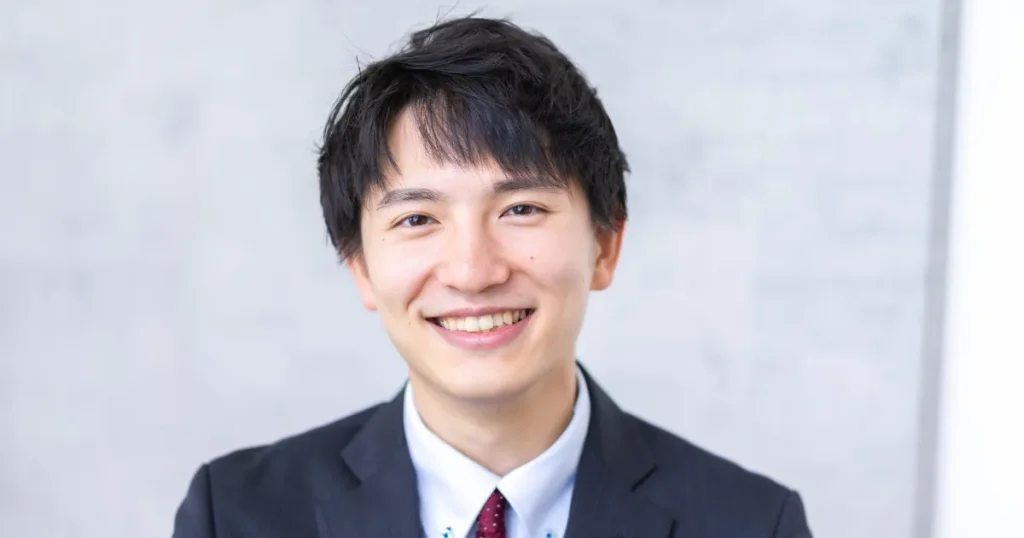 スーツを着た若い男性が笑顔でカメラを見つめている様子。「第2新卒とは何か？」をテーマに、新卒と第2新卒の違いや特徴を解説する内容に関連したイメージ。
