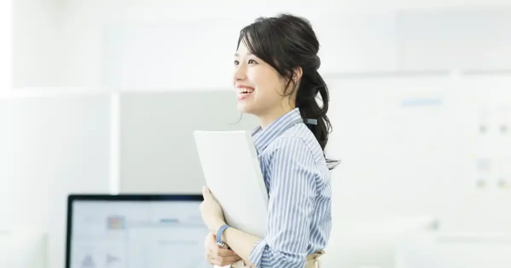 笑顔でファイルを抱える女性の姿。グロサリー部門のアルバイトを通じて身につくスキルや成長の可能性を象徴しています。