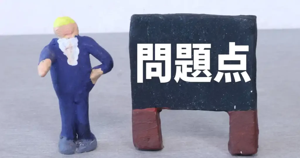 「問題点」と書かれた黒板の隣に立つスーツ姿の粘土人形。課題やデメリットを強調するイメージ。