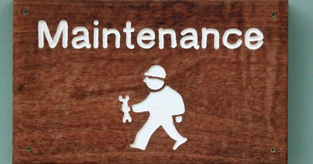 「Maintenance」と書かれた木製の看板に、スパナを持った作業員のシルエットが描かれている。