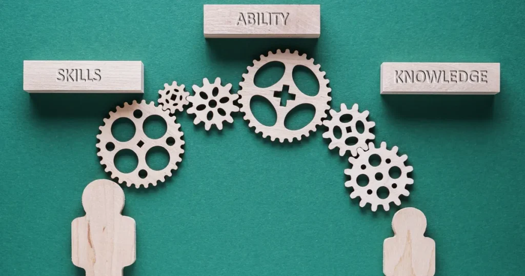 木製のギアが組み合わさり、「SKILLS」「ABILITY」「KNOWLEDGE」と書かれたブロックをつなぐデザイン。社会人基礎力がスキルや知識を活用する土台であることを象徴。