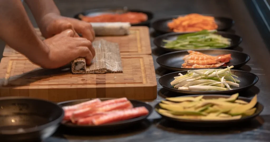 寿司マッチで寿司職人を目指す｜巻き寿司を準備する職人の手元と新鮮な食材が並ぶ調理風景