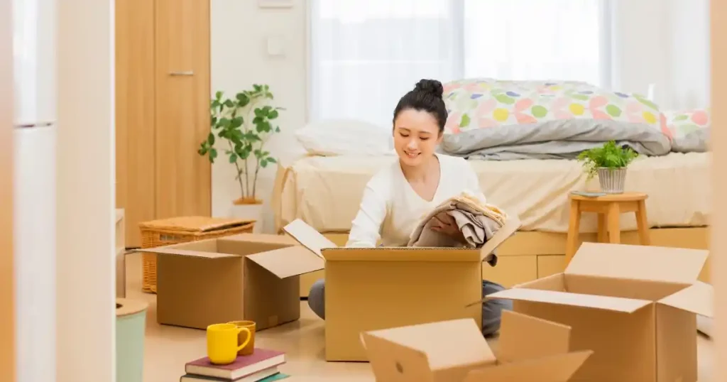 新卒の引っ越しに関するQ&Aセクション。新生活の準備を進める女性が段ボールを整理している様子。