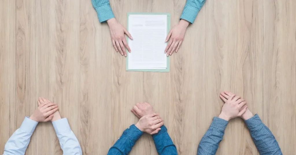 土日面接を希望する際の注意点を説明するセクションに使用される画像。複数人がテーブルを囲み、書類に手を伸ばしている様子を描写。