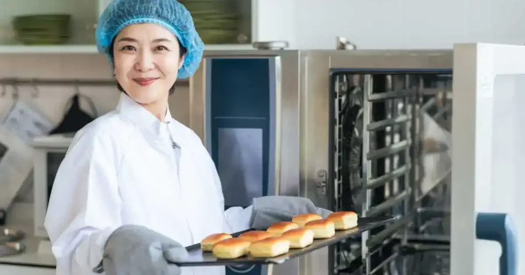 製菓衛生師が焼きたてのパンを取り出している様子。製菓衛生師資格の概要や必要な知識について解説するセクションに関連するイメージ。
