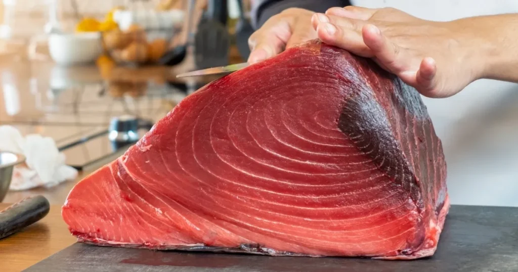 寿司職人が新鮮なマグロの柵を丁寧に扱う様子。寿司職人の経験者がキャリアについて抱える悩みや将来性を象徴するイメージ。