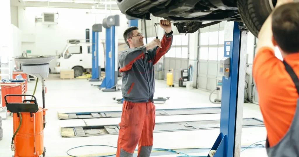 車両をリフトアップし整備作業を行う外国人自動車整備士。日本で整備士として働くための手順や準備について解説するセクションに関連。