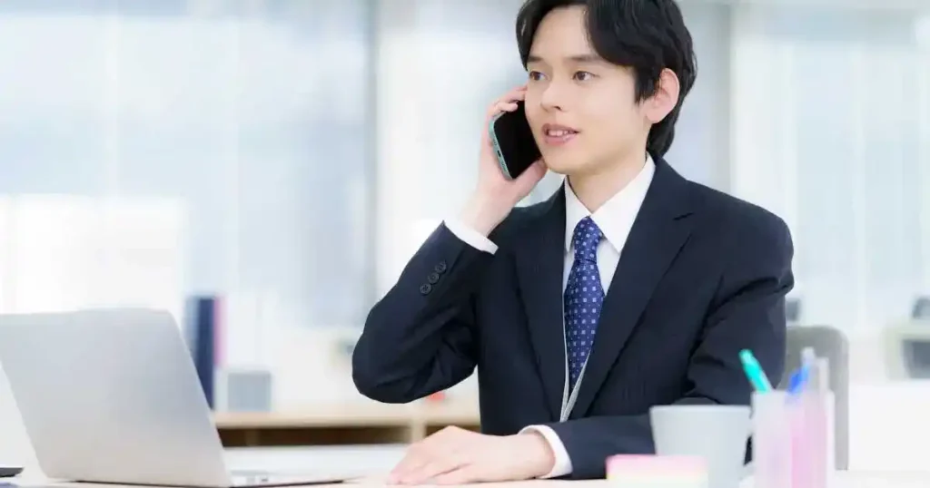 スーツ姿の男性がスマートフォンを使用して電話中。転職活動における電話の問い合わせマナーを象徴するイメージ。