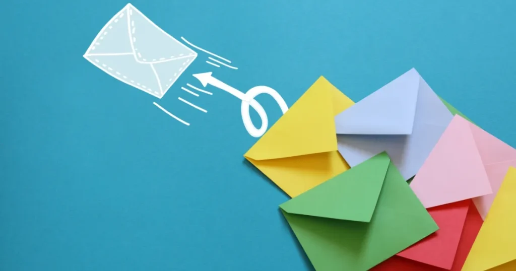 青い背景に並べられた色とりどりの封筒と、飛んでいるメールアイコンのイラスト。就活の問い合わせで返信をもらえない理由について説明するビジュアル。