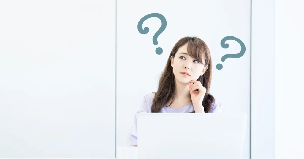 パソコンの前で考え込む女性とクエスチョンマークが浮かぶ背景。面接で逆質問を考える際のポイントを象徴するイメージ。
