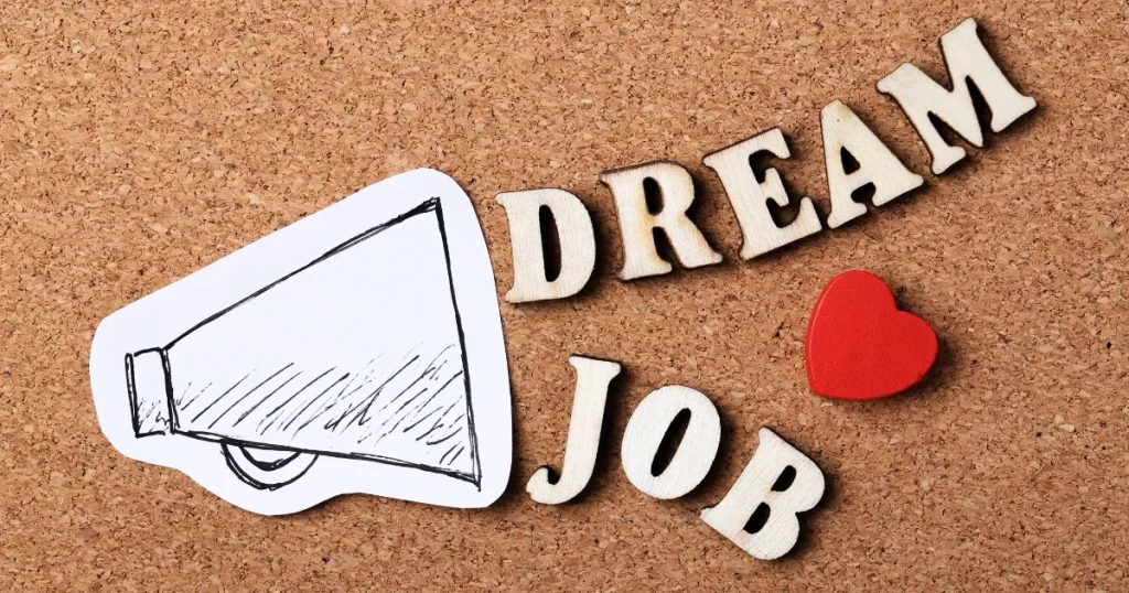 コルクボードに並べた「DREAM JOB」の文字と拡声器、赤いハート。不動産営業で理想のキャリアを目指すイメージ。