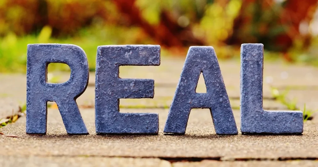 屋外に並べられた「REAL」の立体文字。不動産営業のノルマ・歩合給・休日の実態を紹介するイメージ写真。