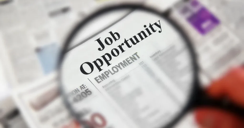 虫眼鏡で新聞の「Job Opportunity」求人欄を拡大し、宅建資格取得後の転職先をチェックする様子