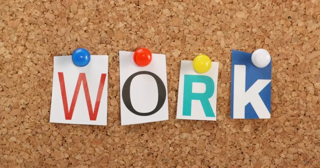 コルクボードにピンで留められた「WORK」の文字で宅建士の独占業務をイメージした画像