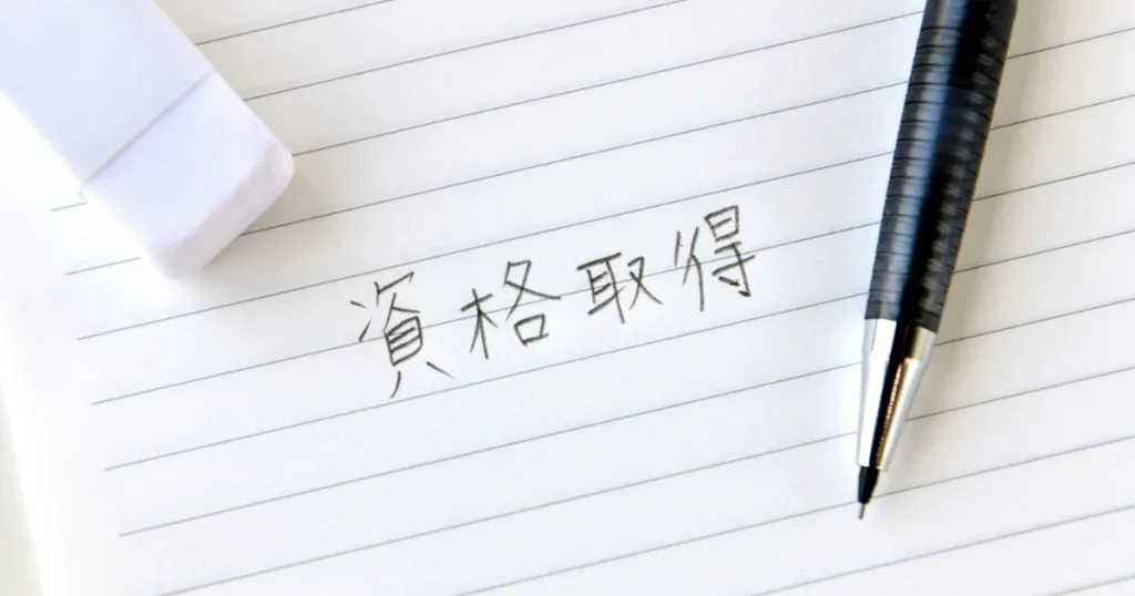 資格取得と書かれたノートとペンで、宅建資格の概要や不動産取引に関する専門知識を表すイメージ
