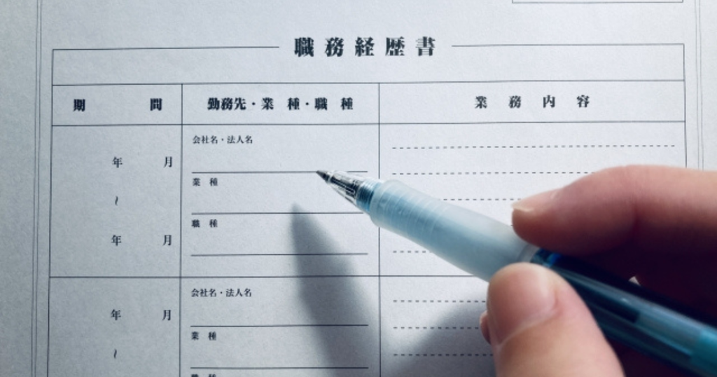 ペンを持って職務経歴書の用紙に記入しようとしている手元で、職務経歴書を何枚にまとめるかをイメージした画像