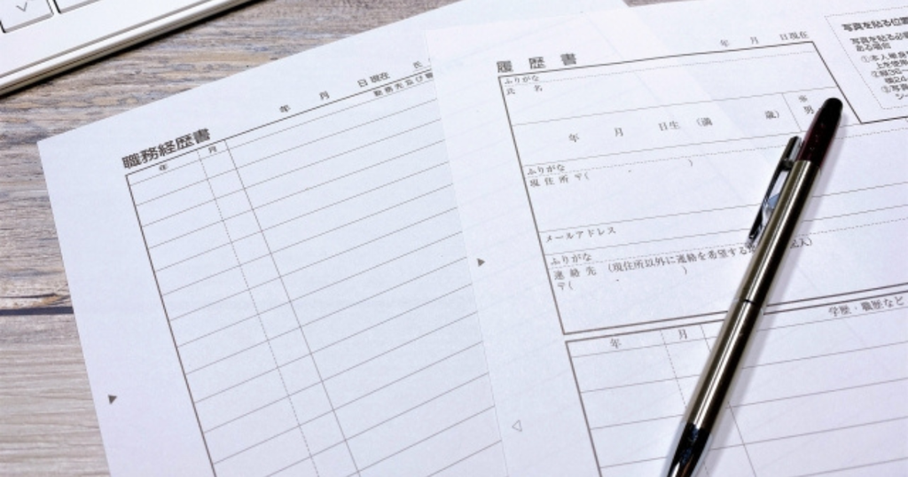 デスクに並べて置かれた職務経歴書と履歴書の用紙とペンで、職務経歴書とは何か、履歴書との違いをイメージした画像