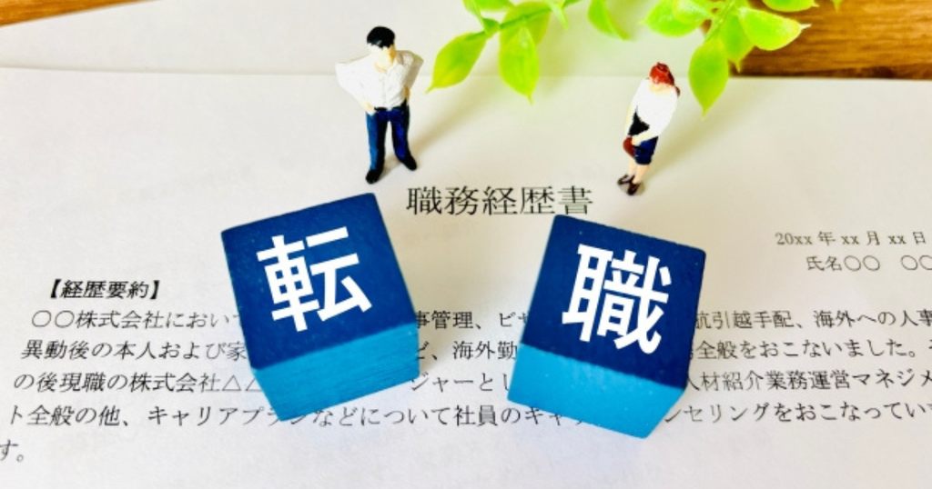 職務経歴書の上に「転職」の文字ブロックと人物の模型が置かれた、転職に向けて職務経歴書を書く前の準備をイメージした画像